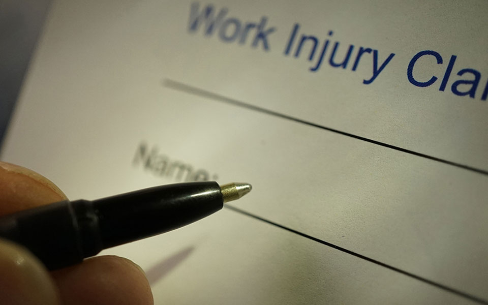 A person filling out a work injury claim form.