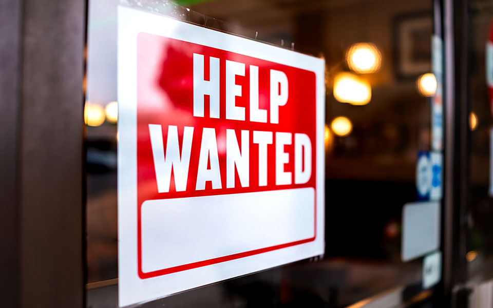 Help wanted sign displayed in a storefront.