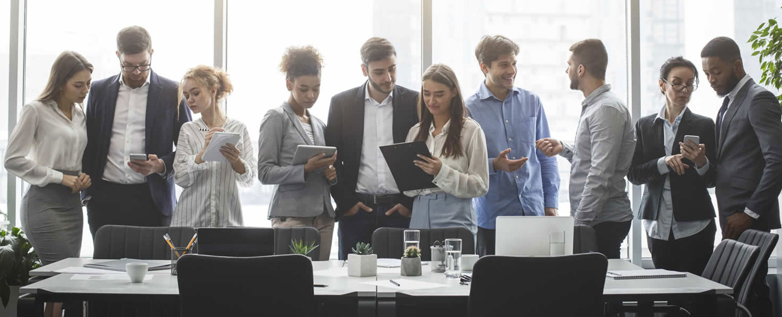 A group of diverse employees standing around and office table.